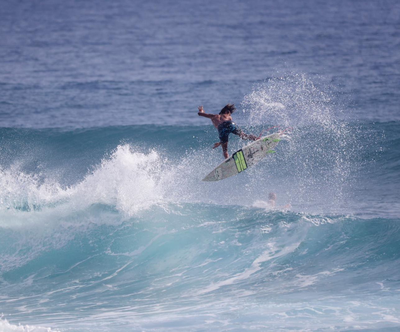 Surfer lifts off above a breaking wave